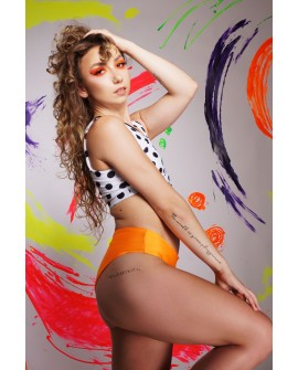 Side view of asymmetrical pole dance shorts in orange with elastic cross strap